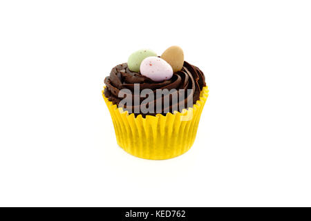 Easter cupcake with chocolate frosting and chocolate Easter eggs on white background with copy space. Stock Photo