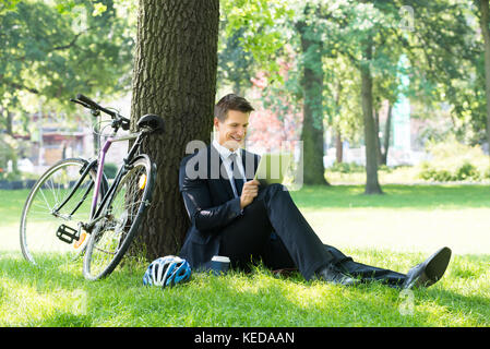 Smiling Young Male Businessman Using Digital Tablet In Park Stock Photo
