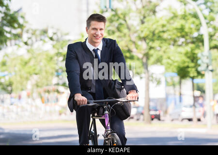 Portrait Of Happy Young Male Businessman Riding Bicycle Stock Photo