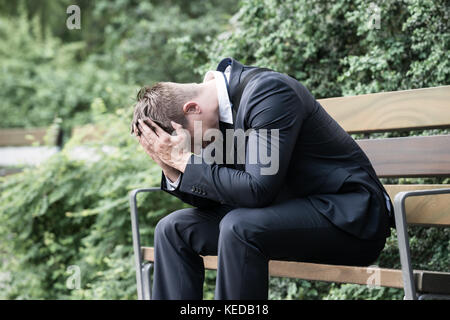 Photo Upset Young Businessman Sitting On Bench Stock Photo
