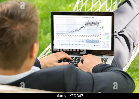 Close-up Of Male Stock Broker Lying In Hammock Using Laptop Stock Photo