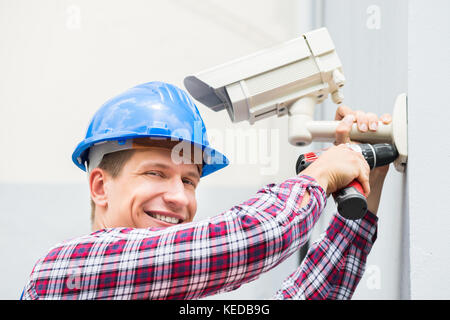 Close-up Of Happy Male Technician Installing Camera On Wall Stock Photo