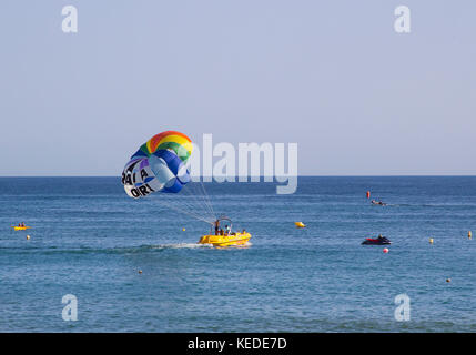 Local instructors prepare their customer for a paragliding experience from the back of their boat at the Praia Da Oura beach in Albuferia in the Portu Stock Photo