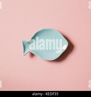 blue empty fish shaped dish on pink background. Flat lay Stock Photo