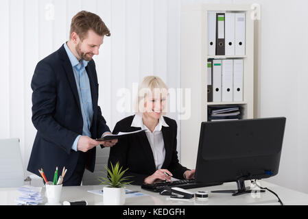 Two Happy Young Businesspeople Working On Computer In Office Stock Photo