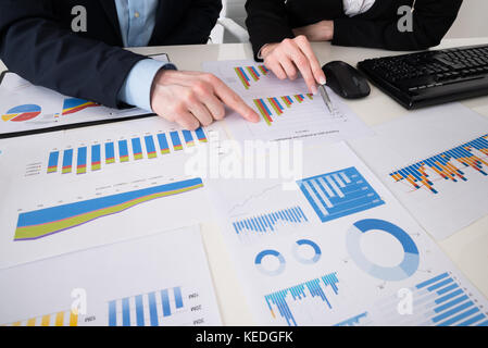 Close-up Of Two Businesspeople Analyzing Financial Graphs In Office Stock Photo