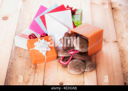 Gingerbread in a gift box near a stack of gifts and multicolored envelopes Stock Photo