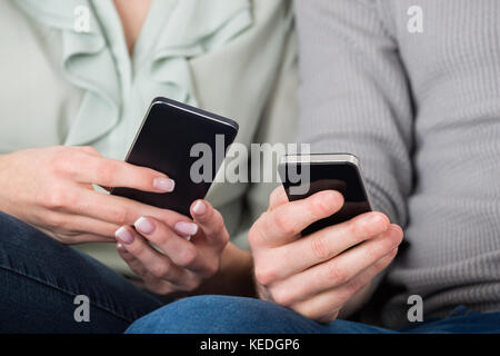 Close-up Photo Of Young Couple Using Cellphones Stock Photo