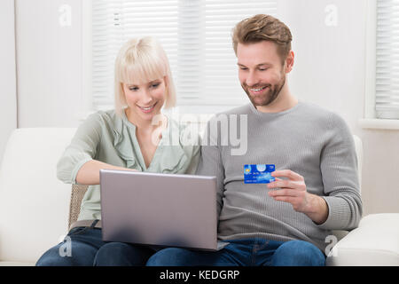 Young Happy Couple Shopping Online Using Laptop Stock Photo