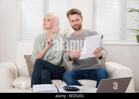 Unhappy Couple Having Argument Over Bill At Home Stock Photo