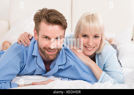 Happy Young Couple Lying On Bed In Bedroom At Home Stock Photo