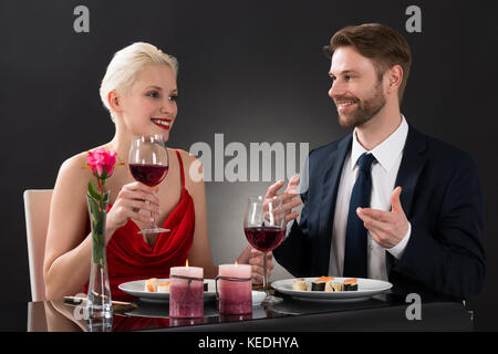Portrait Of A Young Happy Couple Having Dinner In A Restaurant With Black Background Stock Photo