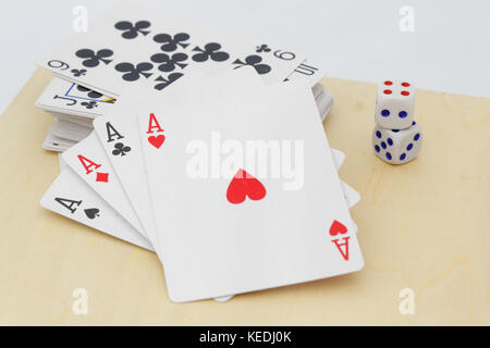 Four aces in front with stack of playing cards at the back with dices on the table. Isolated white background. Stock Photo