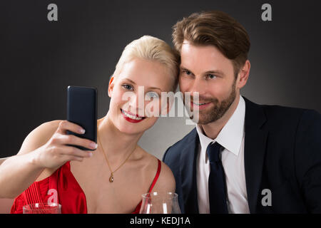 Young Happy Couple Taking Selfie With Their Smartphone In A Restaurant Stock Photo
