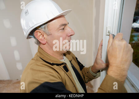master with a screwdriver sets fittings on the window Stock Photo