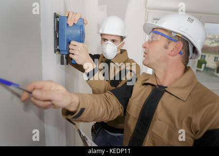 Workman using sander on wall Stock Photo