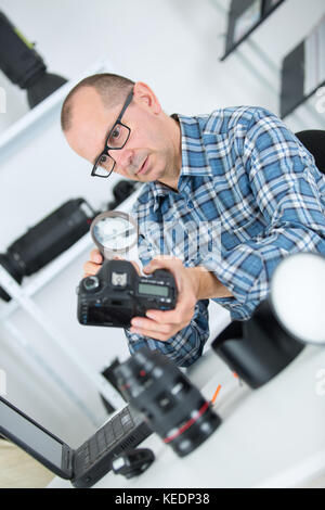portrait of a focused man fixing camera at his workplace Stock Photo