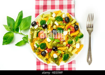 Pasta salad with basil leaves and fork on white Stock Photo