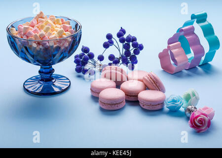 Pink macaroons and marshmallow on blue paper backgrond. Stock Photo