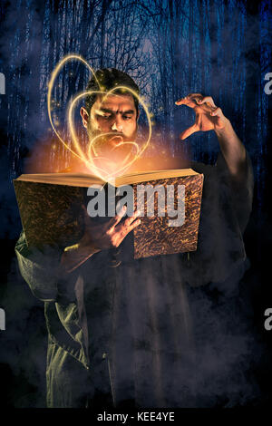 Male sorcerer casting a spell from a magical book as halloween image Stock Photo
