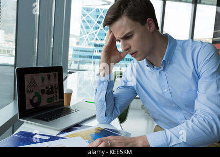 Depressed male executive sitting at desk in futuristic office Stock Photo