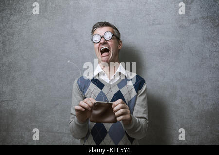 Broke man with thick glasses holding an empty purse and crying, poverty and debts concept Stock Photo