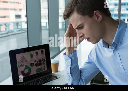 Depressed male executive sitting at desk in futuristic office Stock Photo