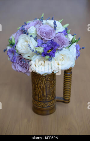 Lavender and roses with purple hues floral arrangement set in a decorated vase with handle Stock Photo