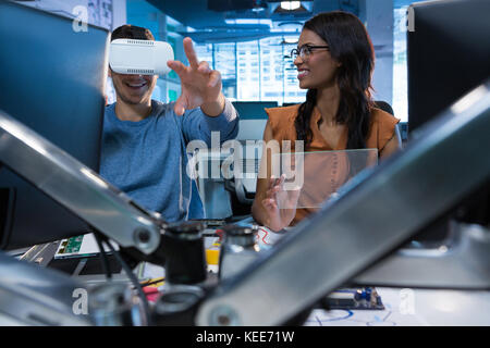 Executives using virtual reality headset at desk in office Stock Photo