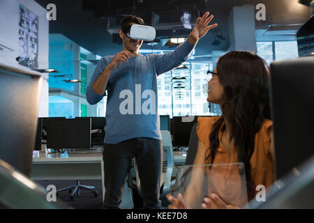 Executives using virtual reality headset at desk in office Stock Photo