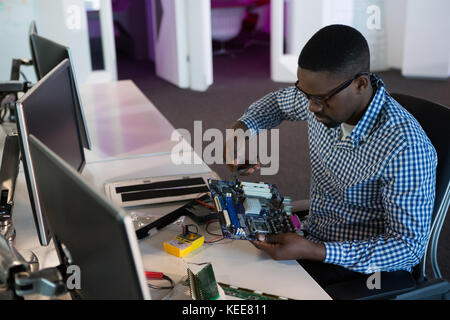 Computer engineer repairing motherboard at desk in office Stock Photo