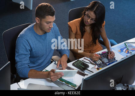 Computer engineers repairing motherboard at desk in office Stock Photo