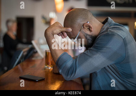 Depressed man standing at counter in bar Stock Photo