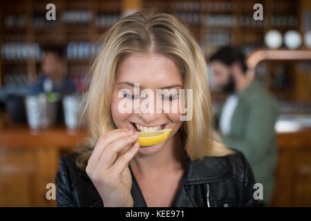 Beautiful woman biting into lemon wedge after having tequila shot in bar Stock Photo