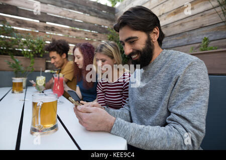Happy friends using mobile phone in bar Stock Photo