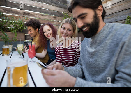 Happy friends using mobile phone in bar Stock Photo