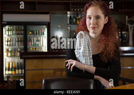 Beautiful waitress standing near bar counter Stock Photo