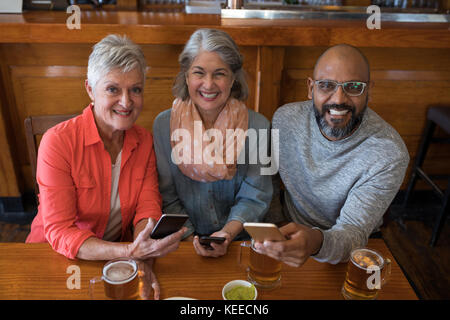 Portrait of happy senior friends using mobile phone in bar Stock Photo