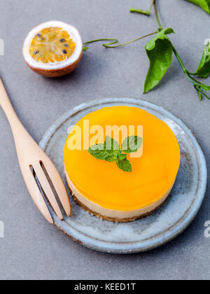 Passion fruit cheesecake with fresh mint leaves on dark concrete background. Passion fruit cheesecake setup with Passion fruit leaves and fresh Passio Stock Photo