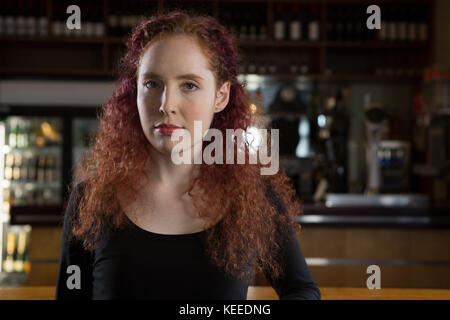 Beautiful waitress standing near bar counter Stock Photo