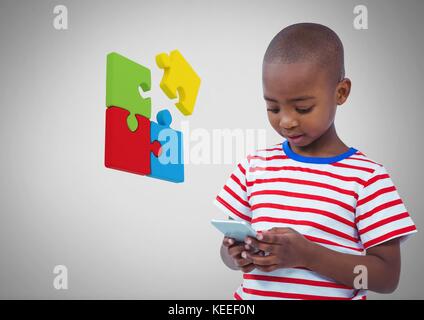 Digital composite of Boy against grey background with phone device and jigsaw puzzle pieces Stock Photo