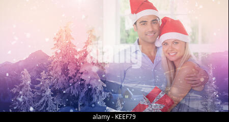 Happy couple at christmas against view of landscape during snowfall Stock Photo