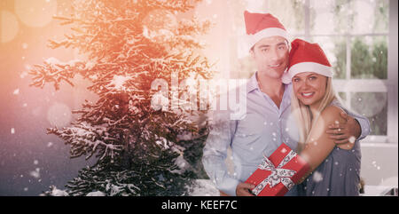 Happy couple at christmas against snow covered trees during winter Stock Photo