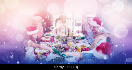 Cheerful family at dining table for christmas dinner against clouds covering snowcapped mountains against sky Stock Photo