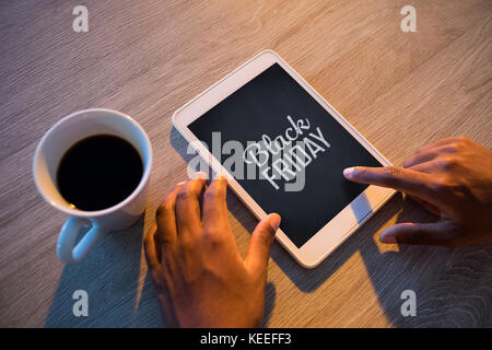Black friday advert against cropped hands of buisnessman using digital tablet at desk Stock Photo