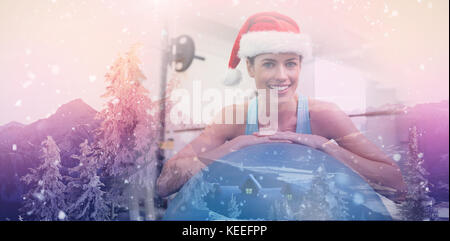 View of landscape during snowfall against women at gym with christmas hat Stock Photo