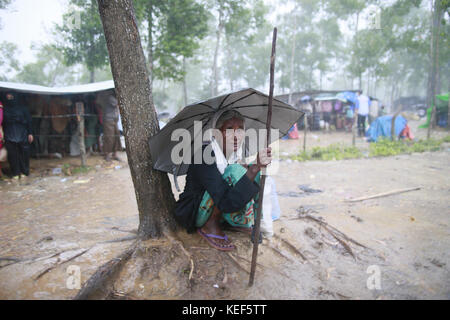 October 19, 2017 - Ukhiya, Bangladesh - Newly arrived Rohingya Muslims sit in the rain covering themselves with plastic sheets at a refugee camp in Ukhiya, Bangladesh, October 19, 2017. Thousands more Rohingya Muslims are fleeing large-scale violence and persecution in Myanmar and crossing into Bangladesh, where more than half a million others are already living in squalid and overcrowded camps, according to witnesses and a drone video shot by the U.N. office for refugees. (Credit Image: © Suvra Kanti Das via ZUMA Wire) Stock Photo