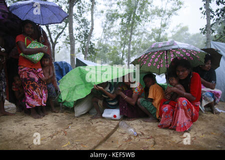 October 19, 2017 - Ukhiya, Bangladesh - Newly arrived Rohingya Muslims sit in the rain covering themselves with plastic sheets at a refugee camp in Ukhiya, Bangladesh, October 19, 2017. Thousands more Rohingya Muslims are fleeing large-scale violence and persecution in Myanmar and crossing into Bangladesh, where more than half a million others are already living in squalid and overcrowded camps, according to witnesses and a drone video shot by the U.N. office for refugees. (Credit Image: © Suvra Kanti Das via ZUMA Wire) Stock Photo