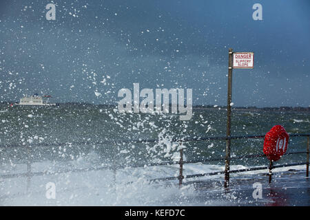Southsea, UK. 21st Oct, 2017. UK Weather. Storm Brian comes to Southsea. Foam and spray breaking over the camera. Isle of Wight ferry on the rough sea. Slippery slope sign and life preserver in the foreground. Credit: David Robinson/Alamy Live News Stock Photo