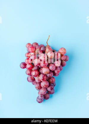 a grape of pink grapes isolated on a blue background Stock Photo